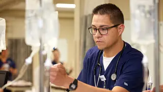 A nurse looks at an IV bag