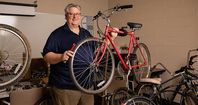 Gray haired man works on a bicycle in a shop.