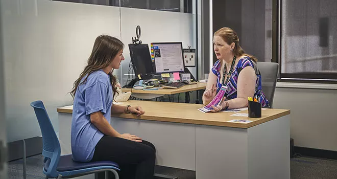 two women sitting across from each other at a desk