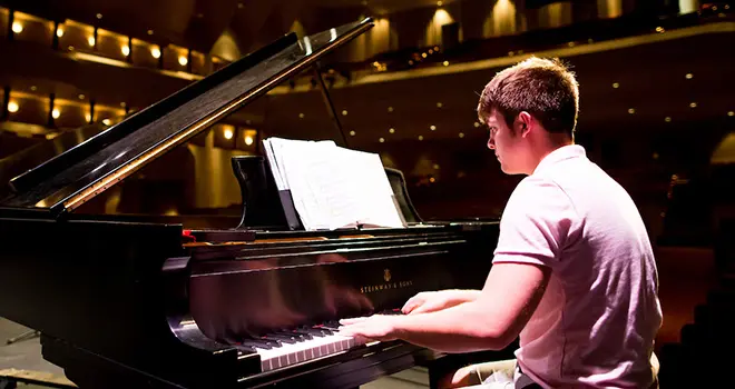 TCC Music student plays a grand piano on stage in the VanTrease Performing Arts Center for Education
