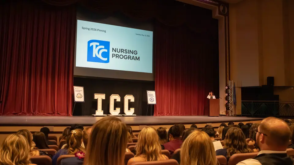 The VanTrease PACE stage is empty before the Nurse Pinning Ceremony begins. There are large white T-C-C letters on stage, and a projector above the letters says TCC Nursing Program.