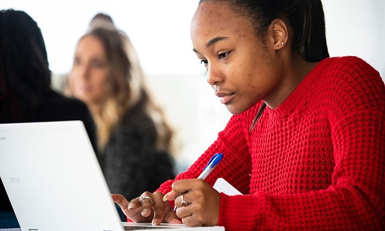 You female TCC student in a red sweater works at a laptop.