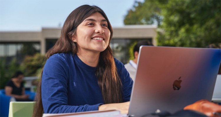 Female tcc student sits at a table outside at southeast campus