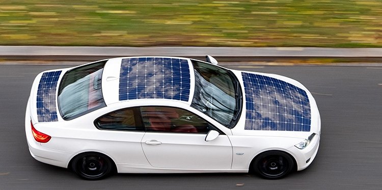 White car covered in solar power cells driving down the road at a high rate of speed.