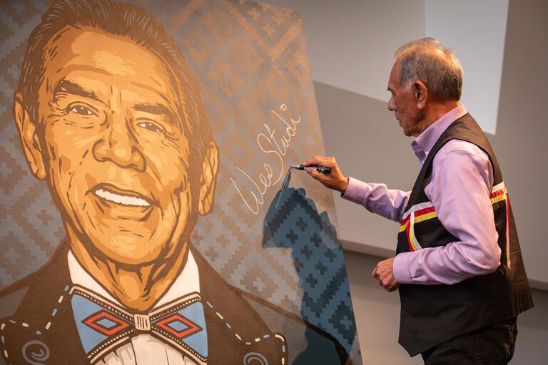 Wes Studi signs a 6-by-5-foot portrait of himself